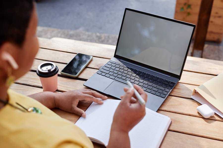 Black senior woman using laptop with blank white screen working outdoors